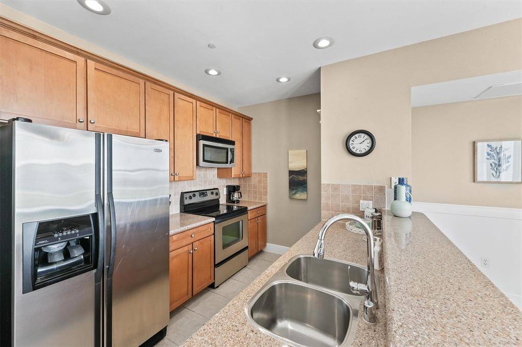 The modern kitchen boasts sleek stainless steel appliances, complemented by warm wood cabinetry. The ample counter space provides a functional and stylish cooking area.