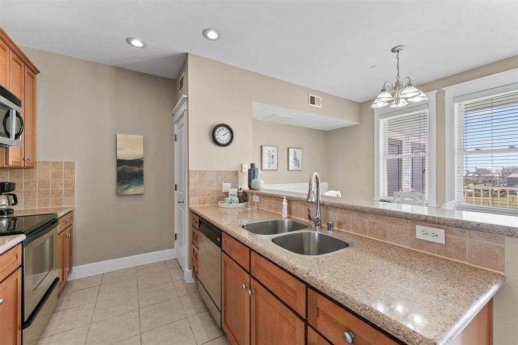 The kitchen features a double sink with a gooseneck faucet, adding both practicality and elegance. The adjacent breakfast bar offers a casual dining option or a spot for quick snacks.