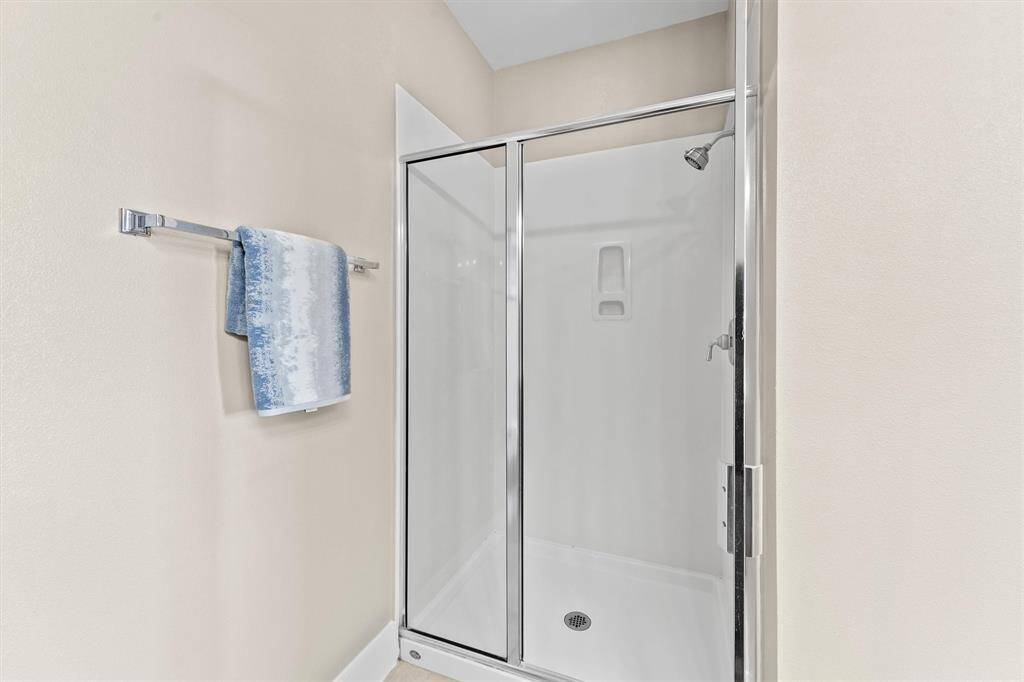 A walk-in shower with a sleek glass door offers a contemporary look and easy access. The neutral color palette and clean lines create a serene and spa-like atmosphere in this primary bathroom.