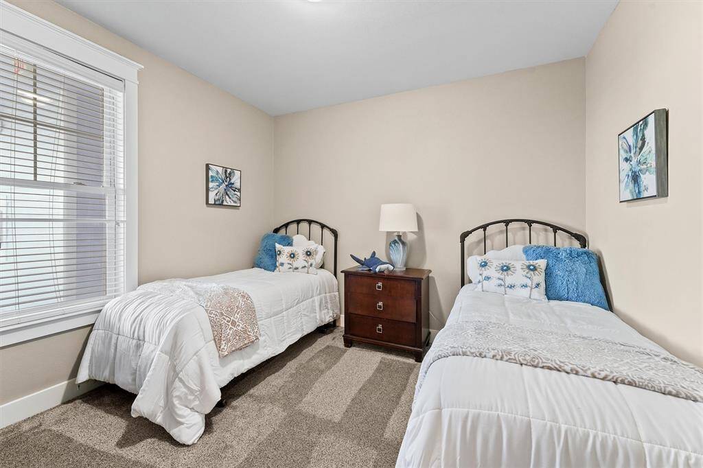 The guest bedroom features ample natural light and neutral wall colors, creating a bright and inviting atmosphere. The soft carpeting underfoot adds comfort and warmth to this cozy space.