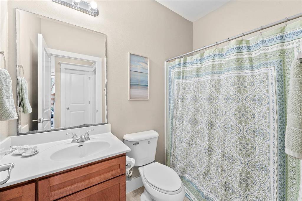 The guest bathroom offers a functional and stylish design with a clean and modern aesthetic. The combination shower and bathtub provide versatility, while the large mirror and bright lighting ensure a well-lit and practical environment.