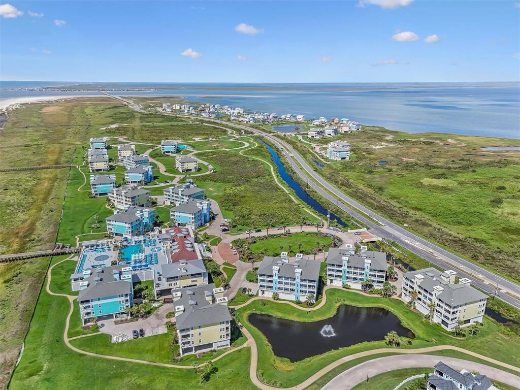 An aerial shot capturing the serene setting of the Pointe West community with its picturesque buildings and the inviting community amenities. The surrounding greenery and water bodies add to the tranquil atmosphere.
