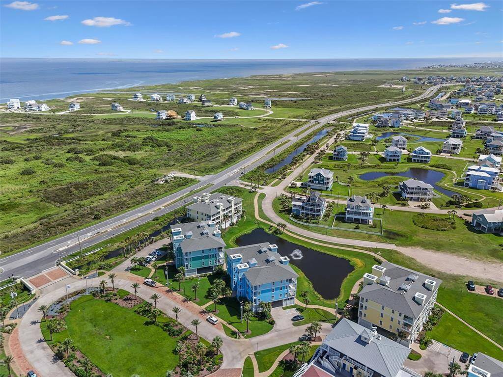 A stunning aerial view of the Pointe West community showcasing the lush green landscape and scenic ocean views. The well-planned layout of the community is evident with the neatly arranged buildings and roadways.