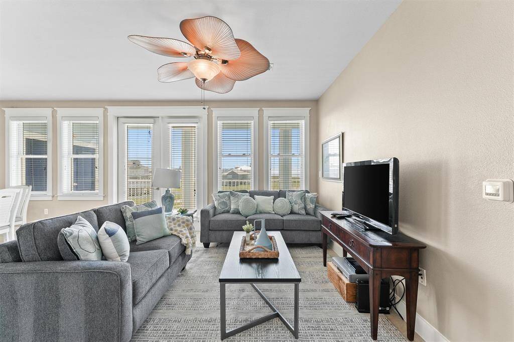 Elegant architectural details, such as high ceilings and a custom ceiling fan, add a touch of sophistication to the living area. These design elements contribute to the room's refined and polished look.