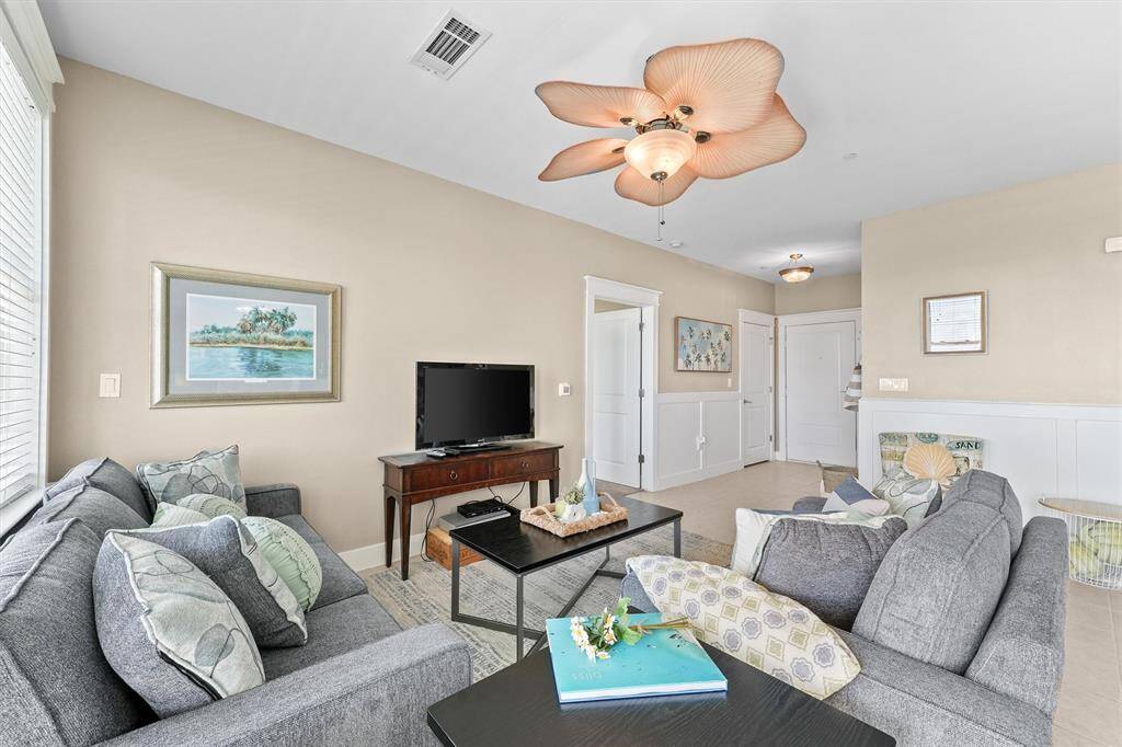 Another view of the living room highlights its spaciousness and modern decor. The comfortable seating arrangement and tasteful coastal-themed decor add a touch of elegance and relaxation to the room.