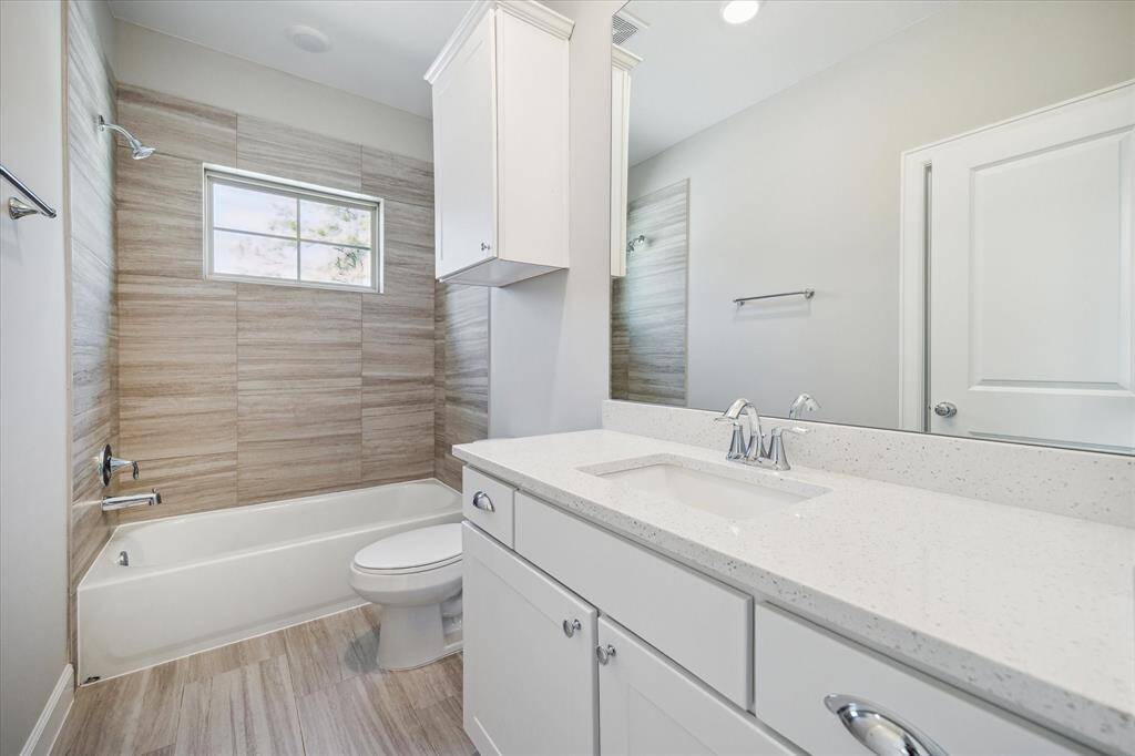 Secondary bathroom with shower/tub combo and quartz counter top.