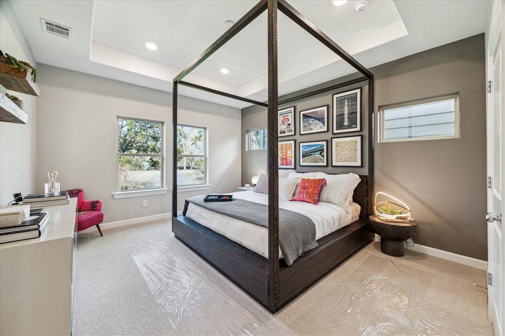 Gorgeous primary bedroom has a raised ceiling and many windows to bring in natural light.