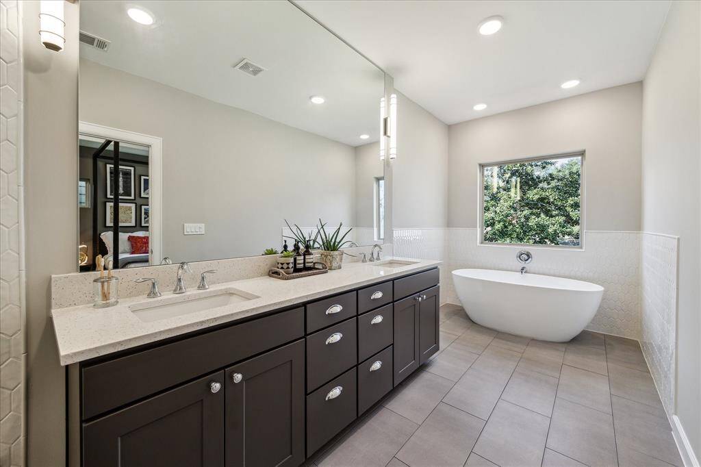 Spectacular primary bath has a freestanding tub, frameless glass shower doors, expanded vanity with two sinks and Moen plumbing fixtures.