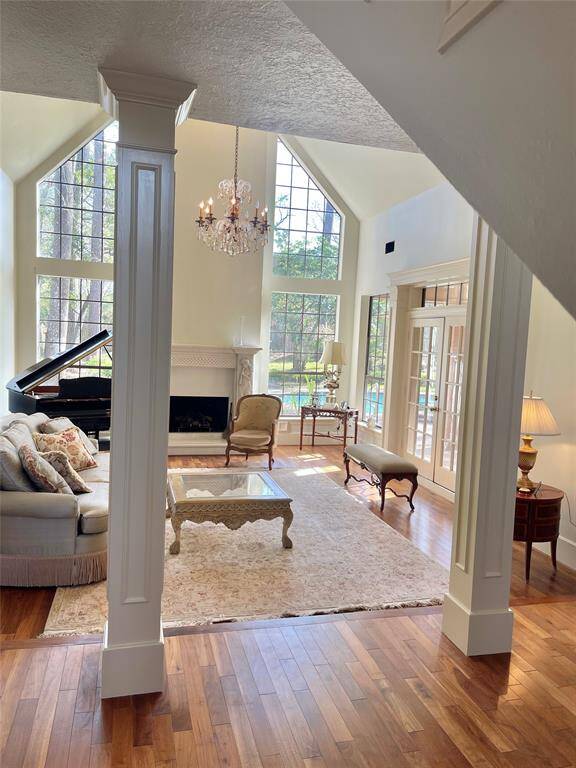 Elegant living room with soaring ceilings, a grand chandelier, and abundant natural light, perfect for relaxation and entertaining.