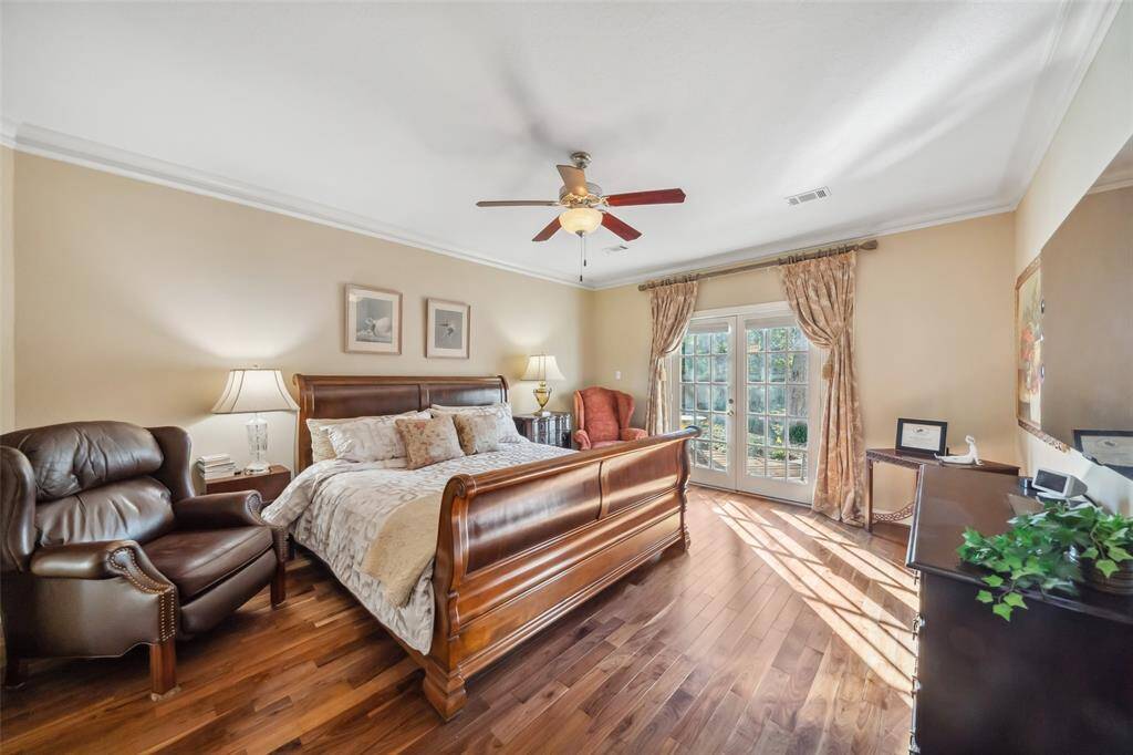 Spacious master bedroom with elegant French doors opening to a serene, park-like backyard.
