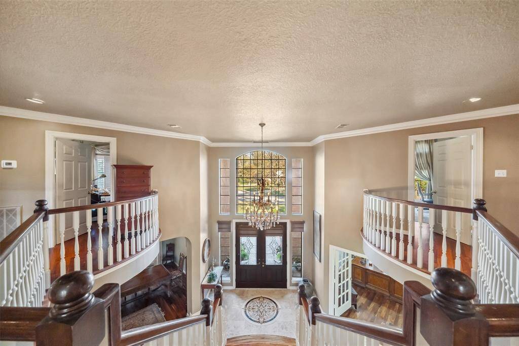 Stunning view from the staircase overlooking the elegant foyer, featuring a grand chandelier and inviting entryway.