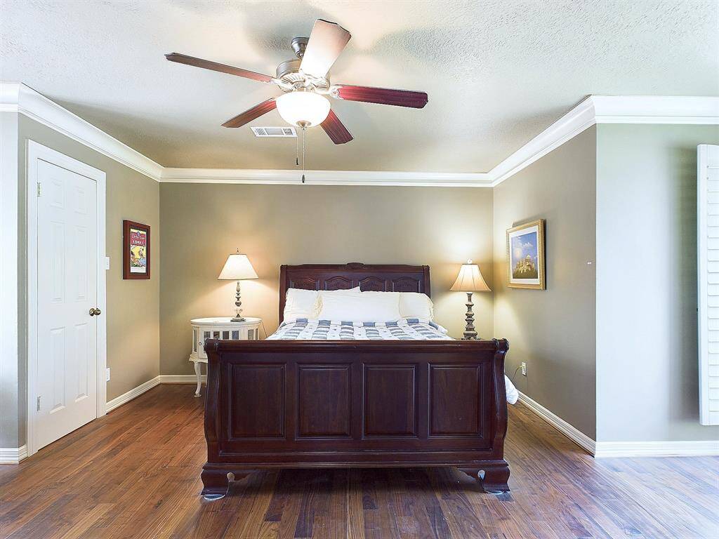 Cozy and inviting bedroom featuring elegant wood flooring, a stylish ceiling fan, and abundant natural light.