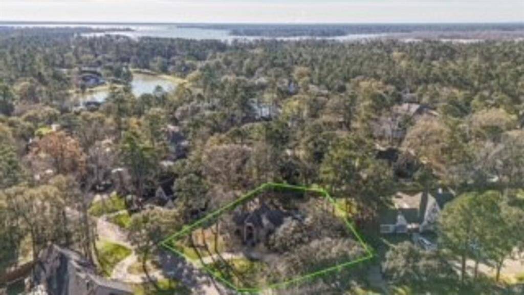 A stunning aerial view showcases this charming home nestled in lush greenery, offering scenic serenity and nearby water views.