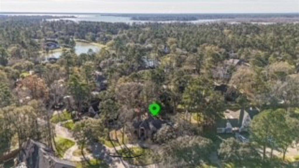 A stunning aerial view showcasing the home's serene setting amidst lush greenery, with proximity to a scenic lake.