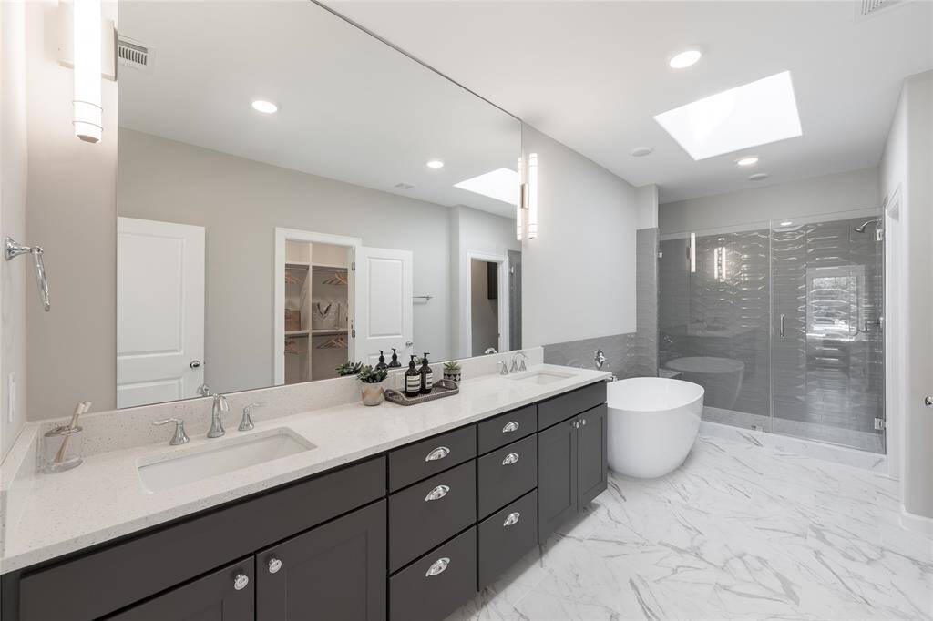 Spectacular primary bath has freestanding tub, frameless glass shower doors, expanded vanity with two sinks and Moen plumbing fixtures.