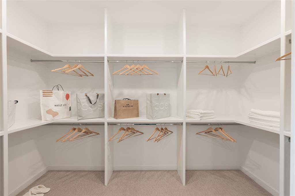 Spacious custom closet with steel rods and plush carpet.