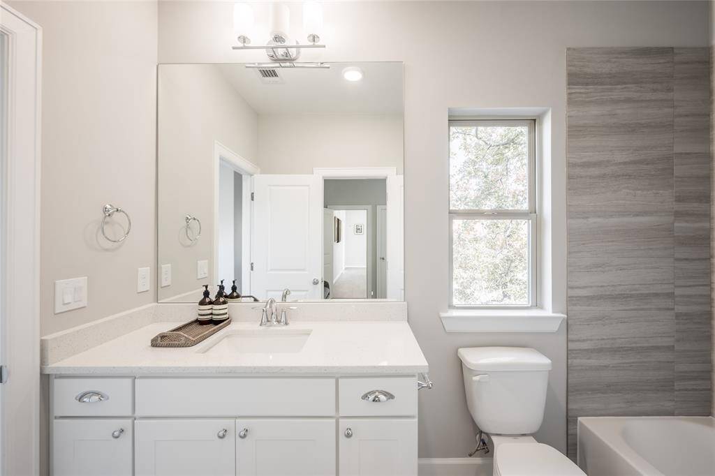 Secondary bath with shower/ tub combo and quartz countertop.