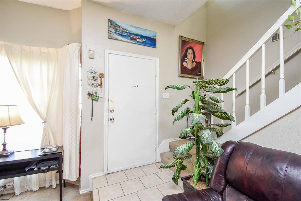 Light, neutral walls and tile flooring fill the front entrance in this inside view, with the carpeted staircase easily accessed.