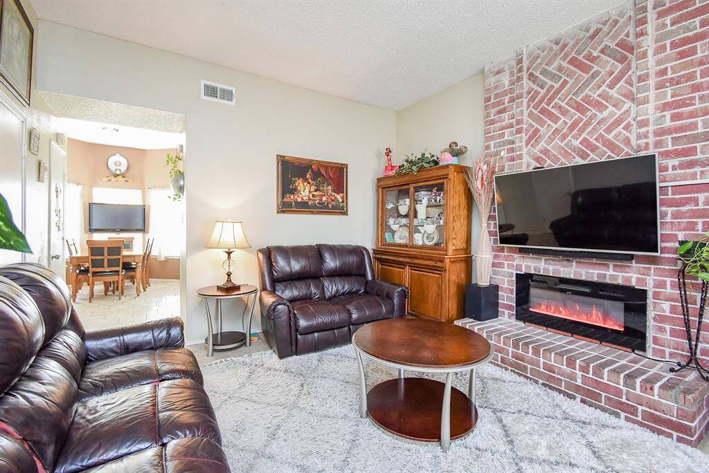 The exquisite floor-to-ceiling brick encased fireplace is sure to be the star of your holiday entertaining in the sizeable living area, with kitchen just footsteps away, left.