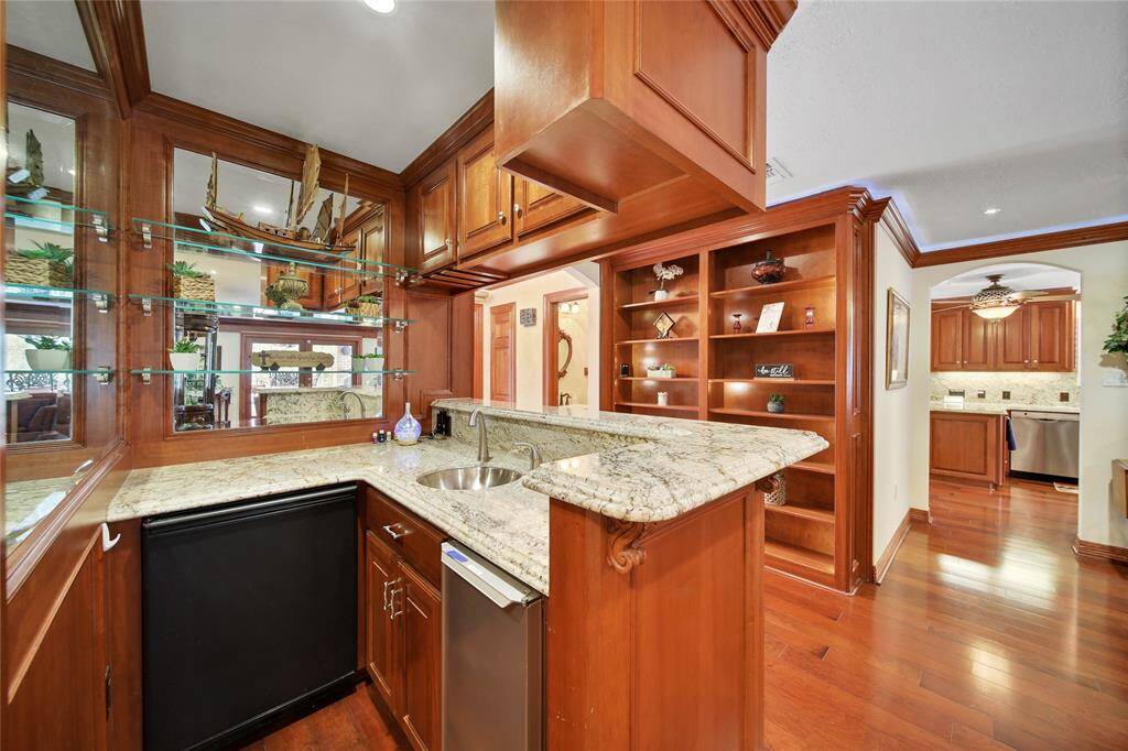 You know you need this bar for holidays and parties! It has a sink, ice machine, refrigerator and EuroCave 3-Temp lockable WINE SAFE!!! Perfect for entertaining! Custom built shelving to display your favorite pieces and half bath is directly across from the wet bar.