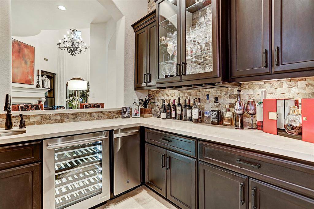 Home Bar | Your friends will love relaxing on the serving bar while you make them drinks in your own home bar with stainless steel beverage fridge, sink, and glass-front cabinets