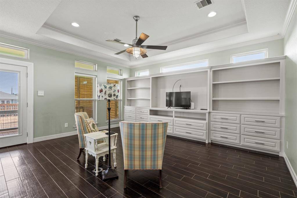 Open floor plan with a wall of built ins, lots of natural light, tray ceiling and wood look tile.