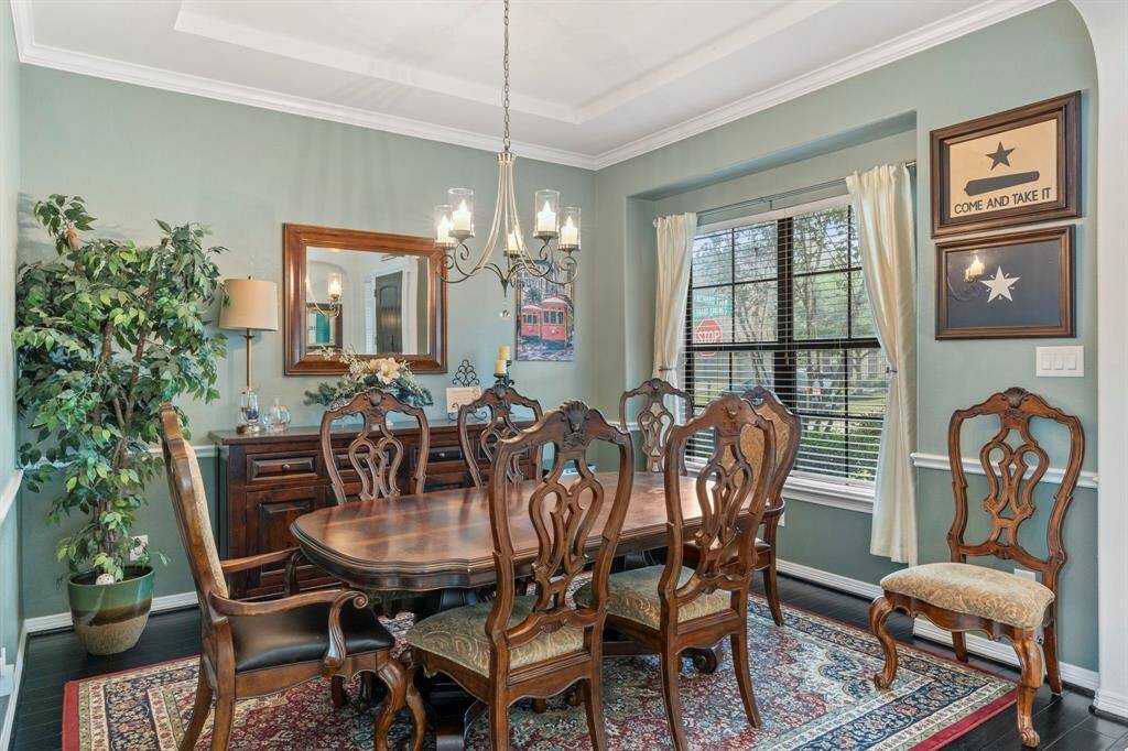 Formal dining area with wood floors, tray ceiling, and crown molding.