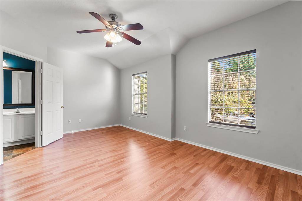 Bright Master bedroom with wood laminate flooring, neutral walls, and a ceiling fan. Two windows provide natural light.