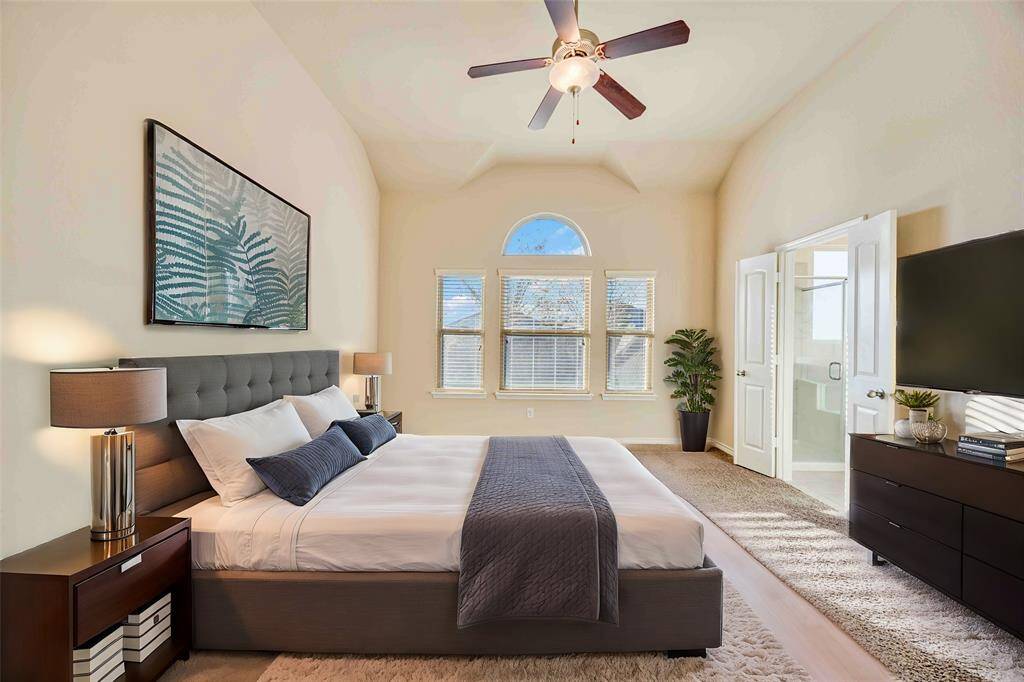 This spacious bedroom features high ceilings, a large arched window for natural light.