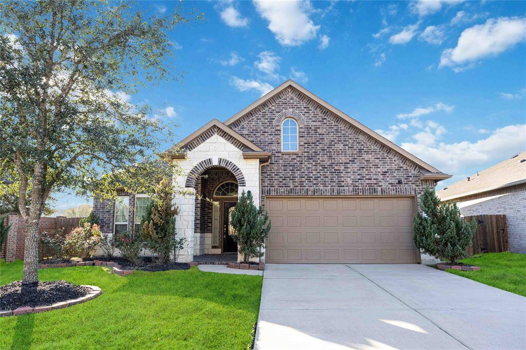 Charming brick home with a well-maintained lawn, arched entryway, and a spacious two-car garage. Perfect for family living in a serene neighborhood.