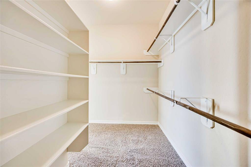 spacious walk-in closet with ample shelving and hanging space, ideal for organized storage.
