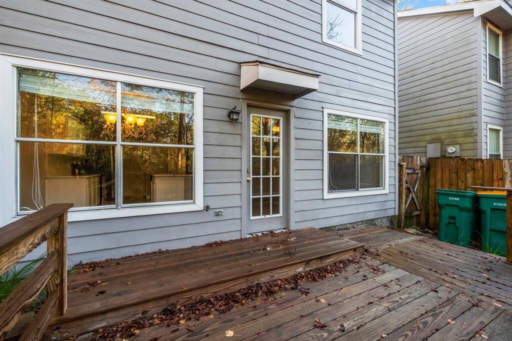 The backyard showcases a cozy backyard deck with wooden flooring, adjacent to a gray siding house. Large windows allow plenty of natural light inside, and a glass door provides easy access to the deck. The space is fenced for privacy.