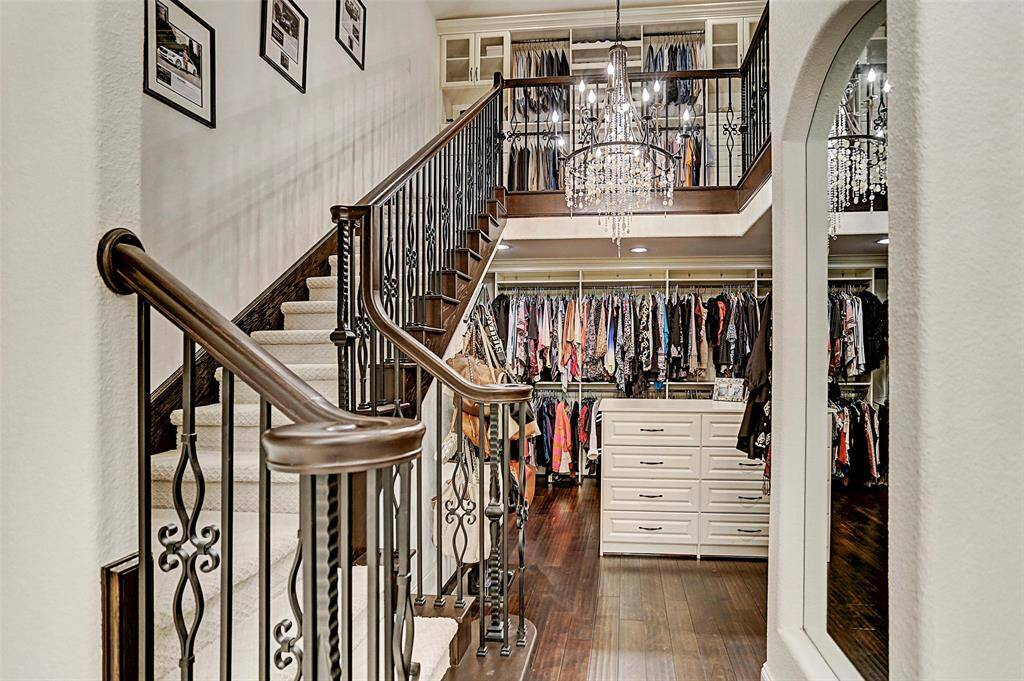 Two-Story Master Closet | This closet truly completes the boutique spa bath with a built-in dressing counter, hardwood floors, wrought iron staircase, designer chandelier and plenty of space for all the clothes you could ever want!
