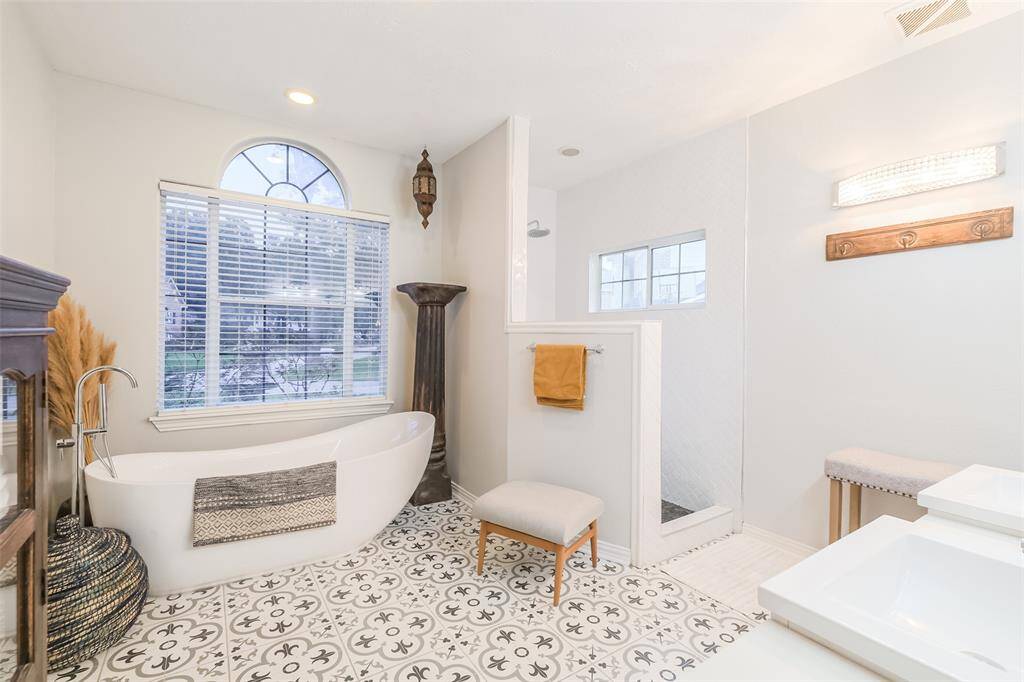 Primary bathroom newly updated tile floors with walk-in shower and separate tub