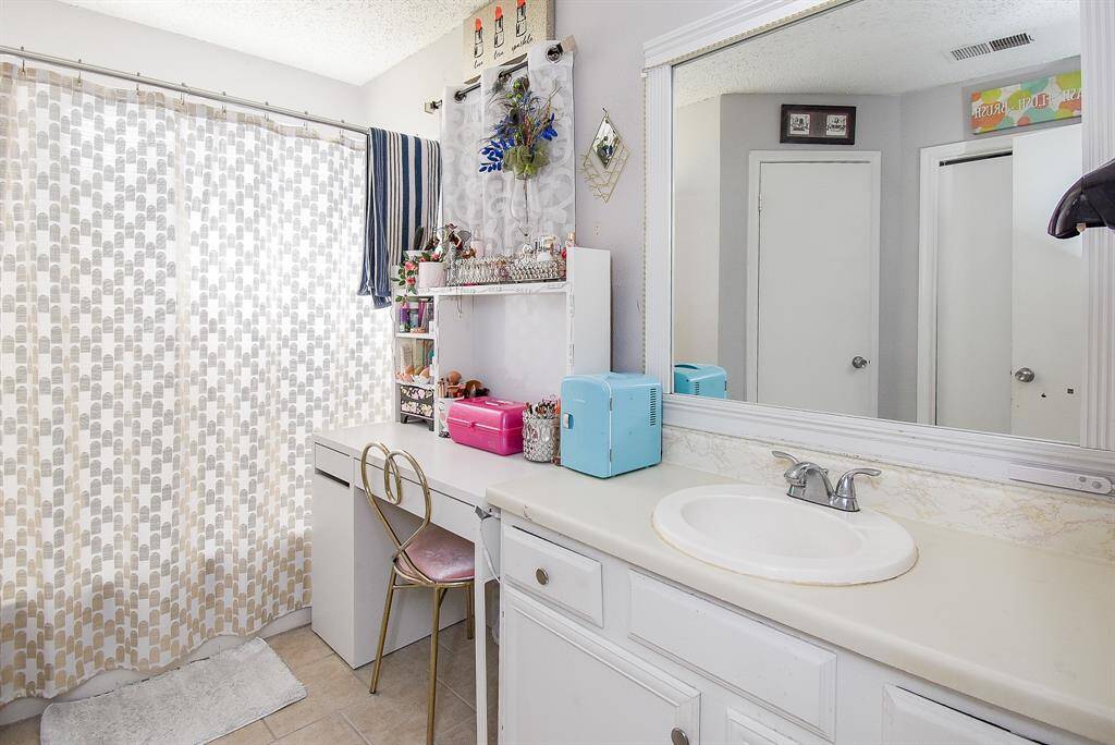 A single sink/vanity and lots of counter space fill the primary ensuite bath, with a good looking framed wall mirror and bright lighting, above.