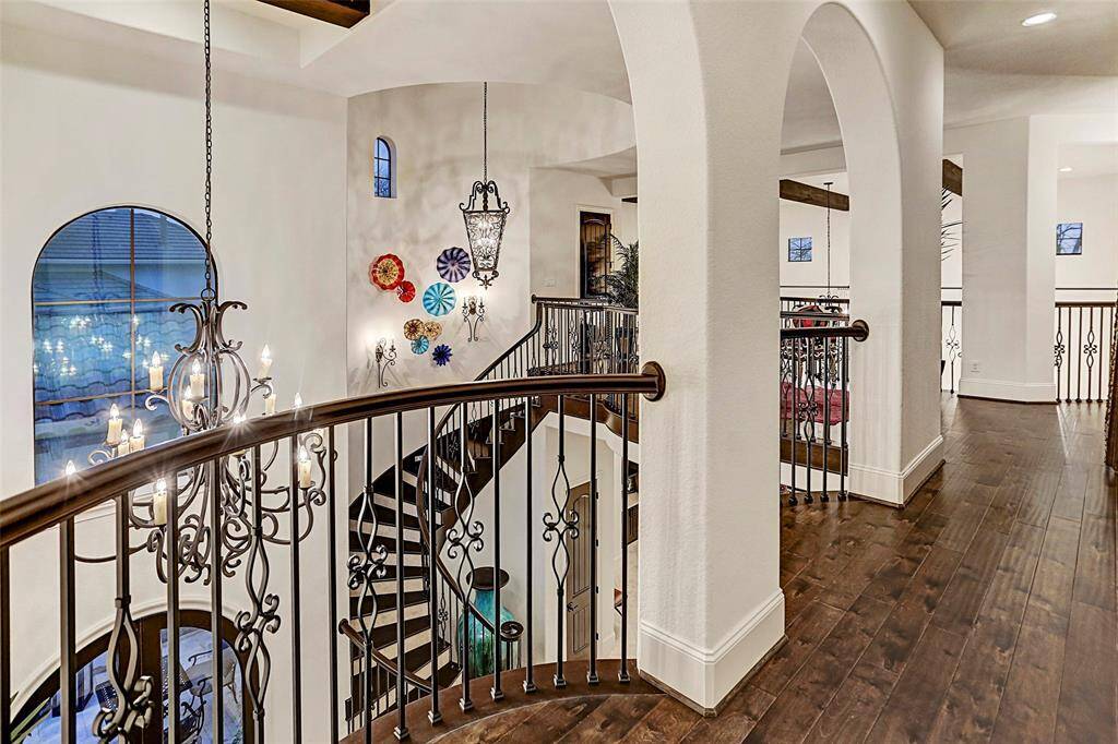 Upstairs Landing | This breathtaking view truly showcases the beautiful curved wrought iron stairwell and custom lighting found throughout the home
