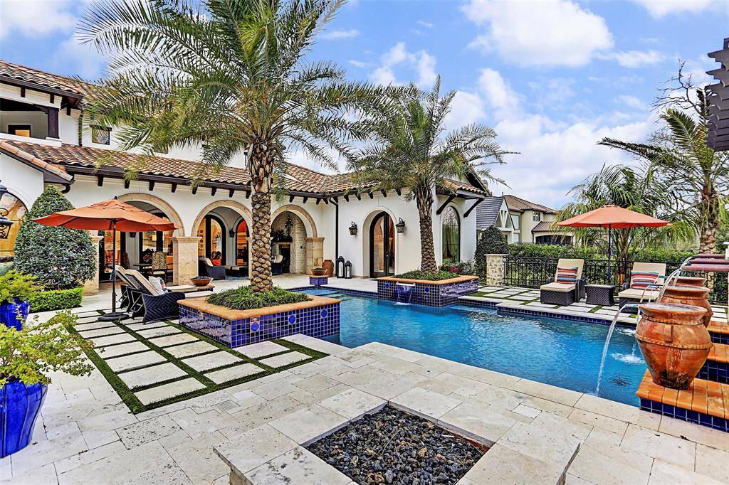 Landscaping | The mature palm trees with tile surrounds, travertine decking and custom stone with grass accents just add to the luxurious feeling of this backyard oasis