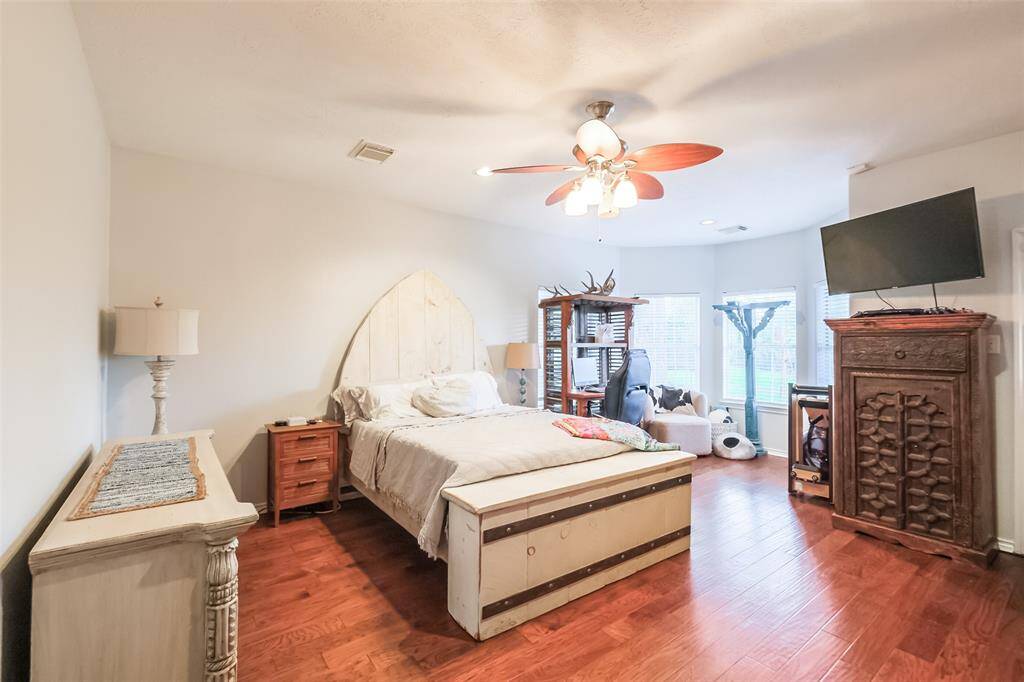 Primary bedroom with wood floors and seating area overlooking spacious backyard