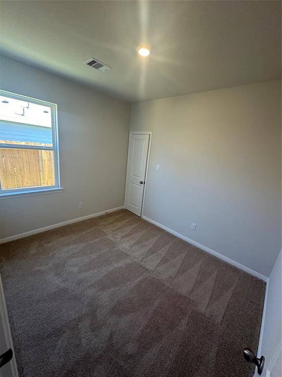This spacious second bedroom is filled with natural light from a large window, creating a bright and airy atmosphere.
