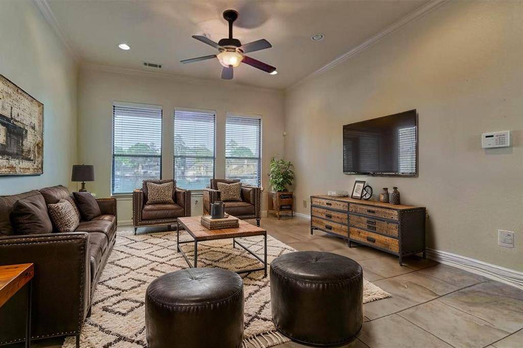The living room features three large windows that frame beautiful views of Lake Conroe, filling the space with natural light and scenic charm. This photo has been virtually staged to show furniture placement.