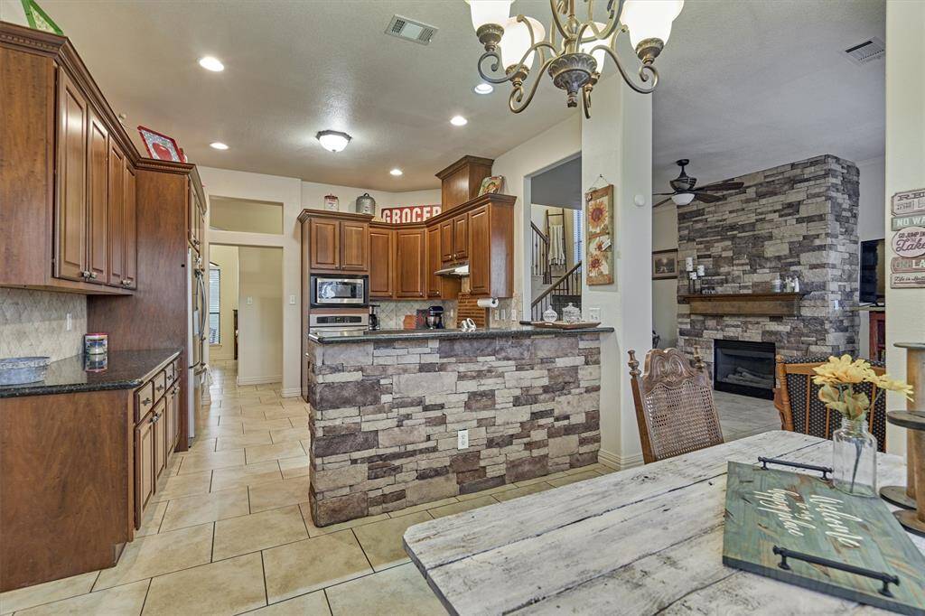 Stone accents on the breakfast bar complement the matching stonework on the fireplace, creating a cohesive and warm design throughout the living space.