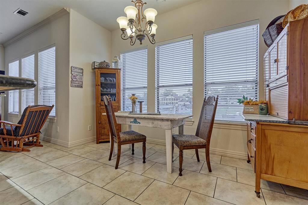 The breakfast area offers serene views of the backyard and lake, with a convenient access door leading directly to the back patio—perfect for indoor-outdoor living. This photo has been virtually staged to show furniture placement.