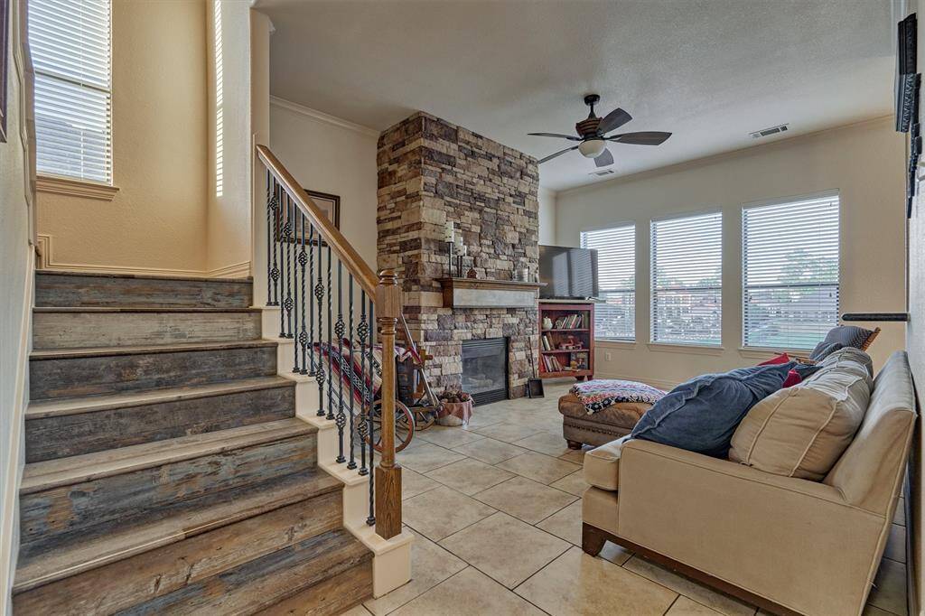 Beautiful wrought iron and wood railing adds an elegant touch to the staircase, perfectly complementing the rich wood tones of the stairs and stone fireplace.
