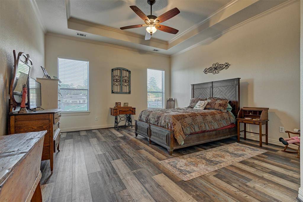 The spacious primary bedroom showcases a tray ceiling, luxury vinyl flooring, and large windows that capture stunning views of the lake.
