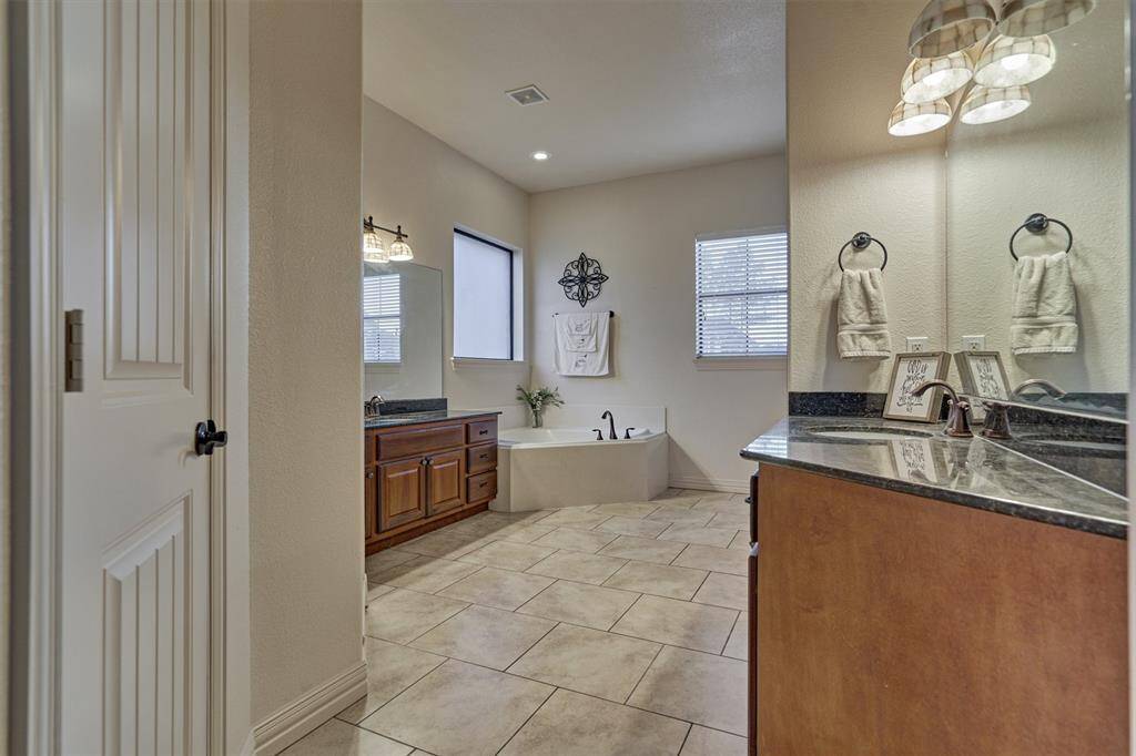 The primary en-suite bath features a jetted corner tub, dual vanity areas for added convenience, and two separate closets offering ample storage space.