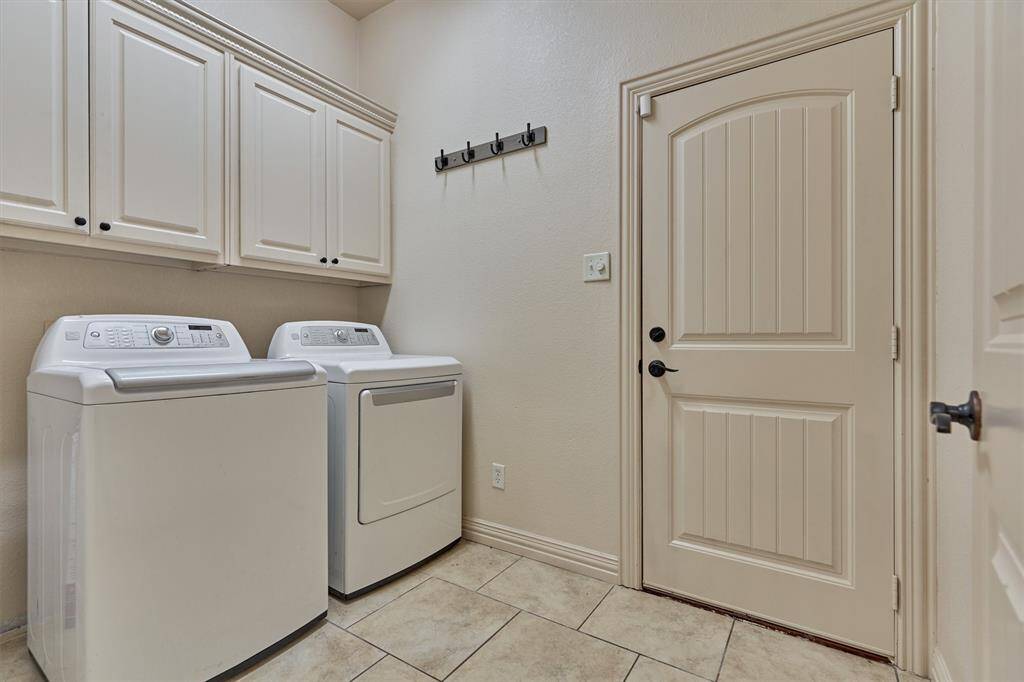 The spacious laundry room features built-in storage cabinets and provides direct access to the garage.