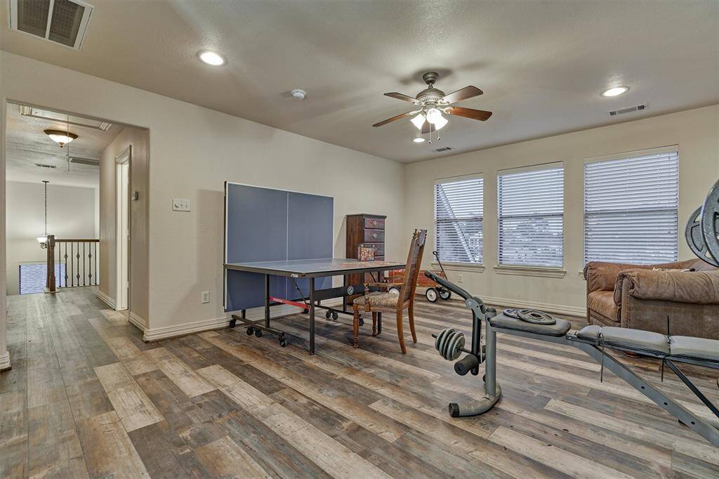 Another view of the game room highlights its generous size and offers a glimpse down the hallway leading to the staircase.