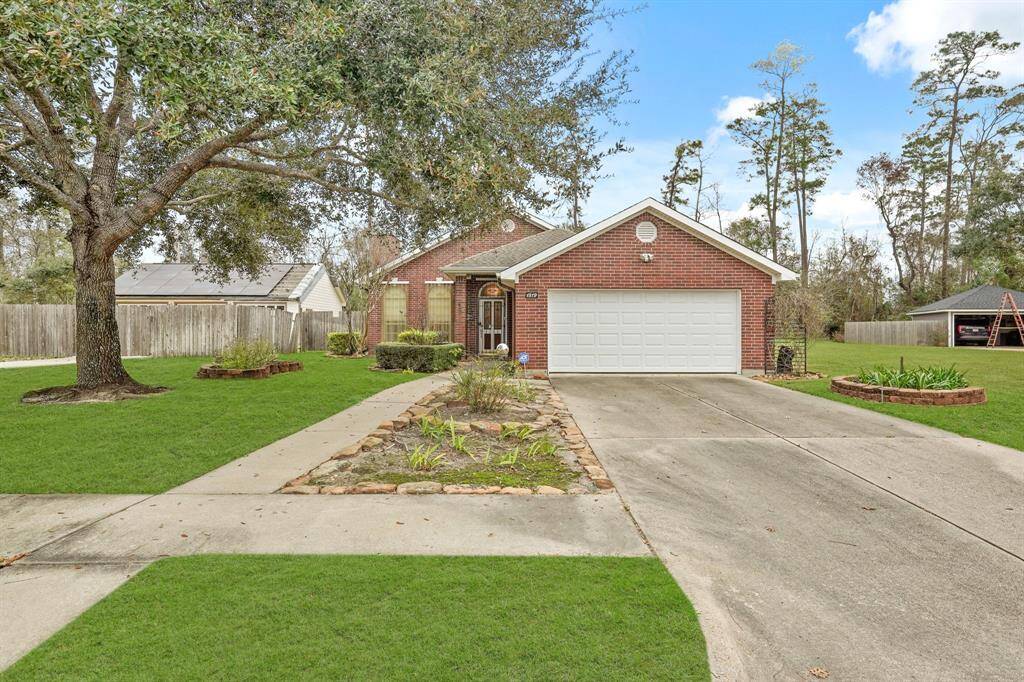 This charming brick home features mature trees and landscaped flower beds. It includes a two-car garage and a spacious driveway, set in a serene neighborhood with ample greenery.