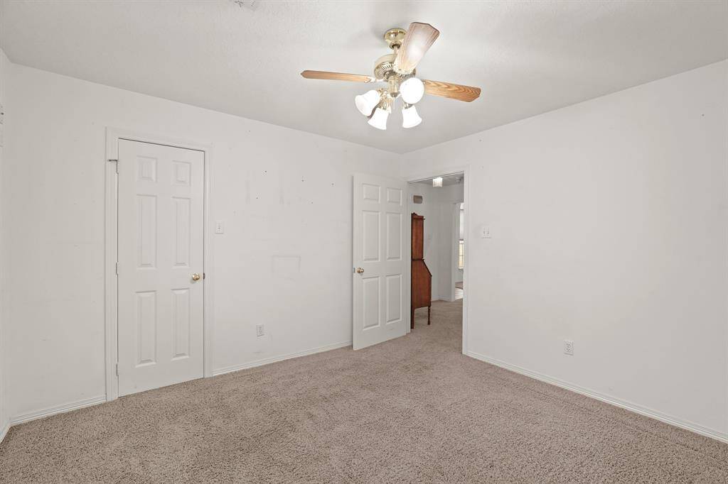 This room features neutral carpet and walls, a ceiling fan, offering a simple and versatile space.