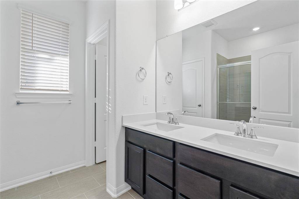This primary bathroom is definitely move-in ready! Featuring stained cabinets with light countertops, dual vanities, high ceilings, custom paint, sleek and dark modern finishes.